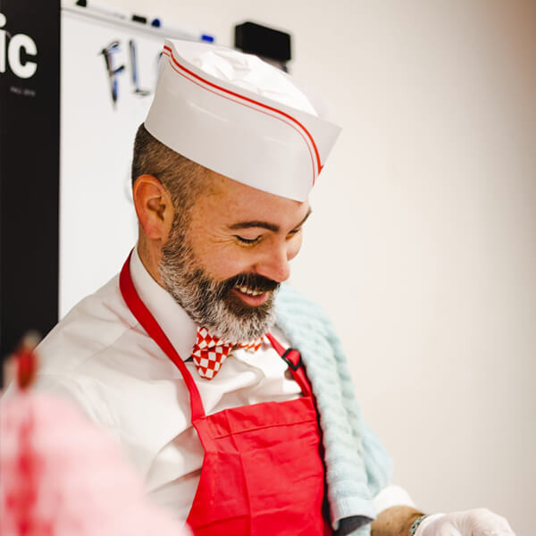 A man dressed in a white chef's coat and hat.