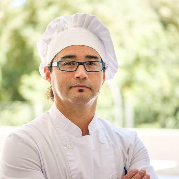 A man dressed in a white chef's coat and hat.